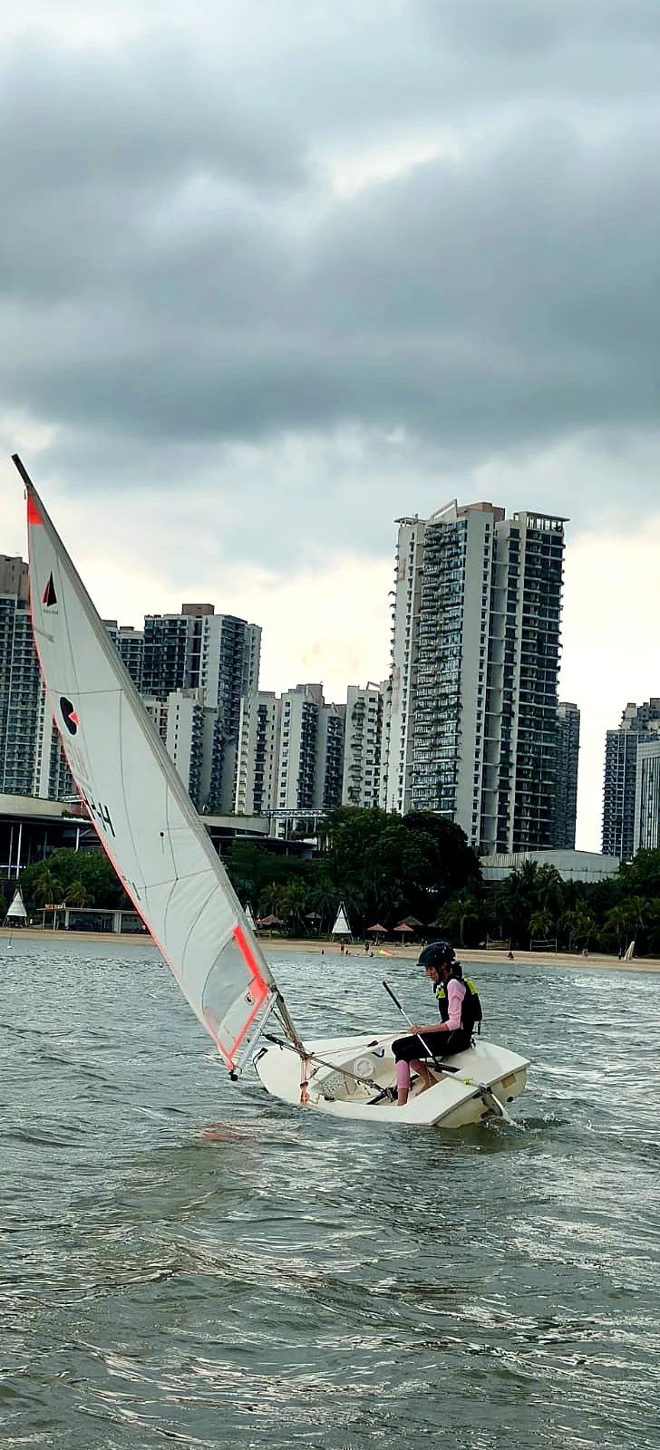 A dinghy sailor steering beside Forest City