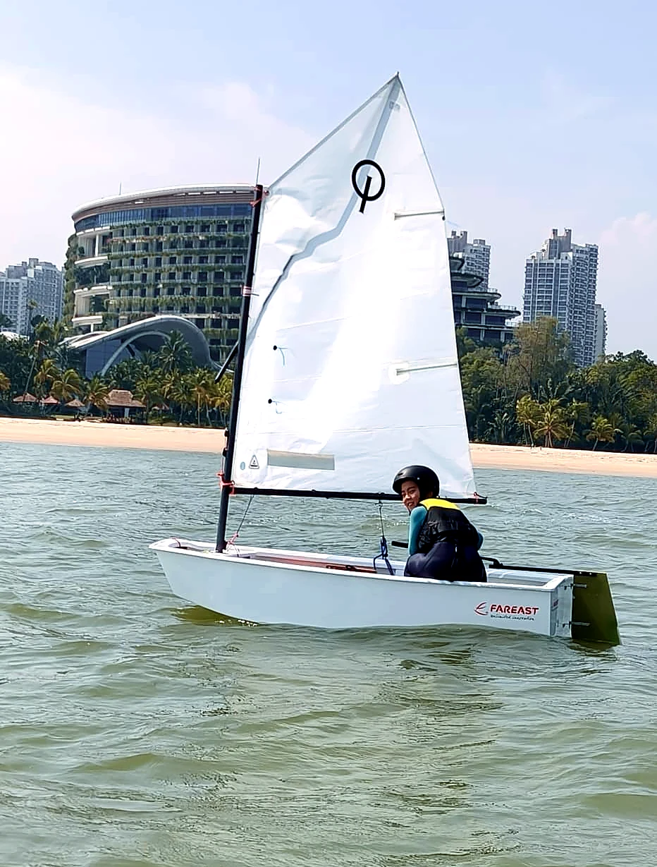 A SeaQuest sailor at the helm of an Optimist dinghy
